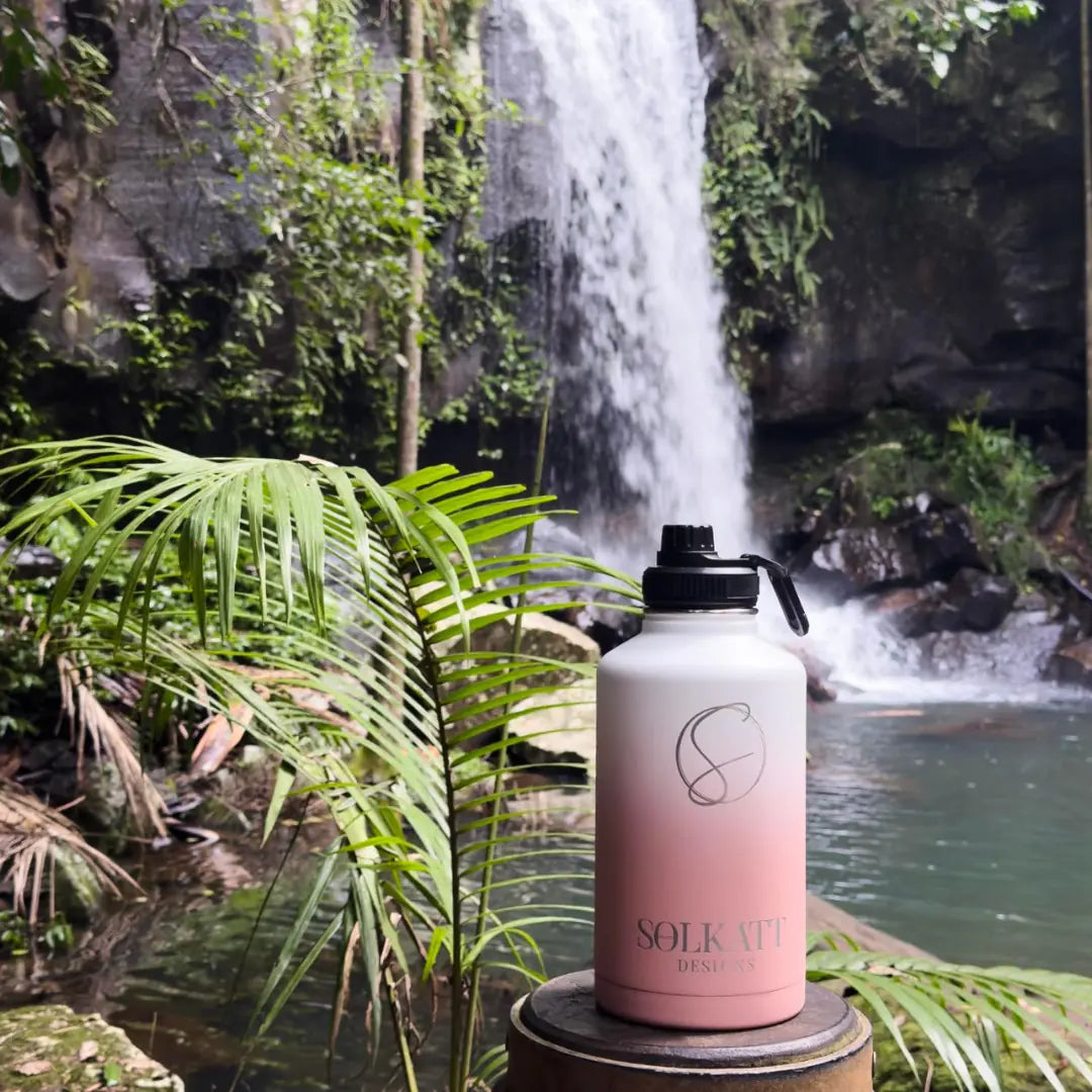 Coral pink 1.9 litre water bottle visiting cedar creek falls in QLD australia